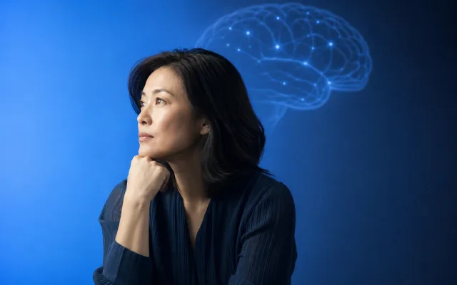 Adult sitting quietly with a softly glowing brain outline above, suggesting research and gentle inquiry into long-term brain health