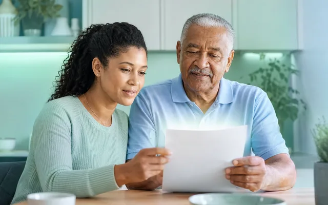 An adult child and an older parent reviewing a Medicaid benefits letter together at a kitchen table